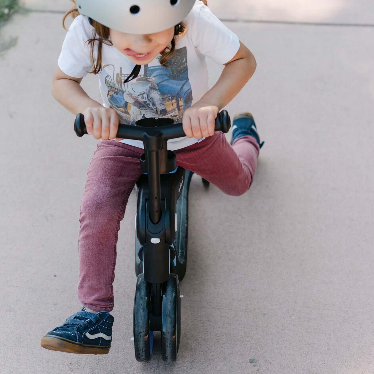Child with tounge poking out riding Larktale Scoobi in balance bike mode