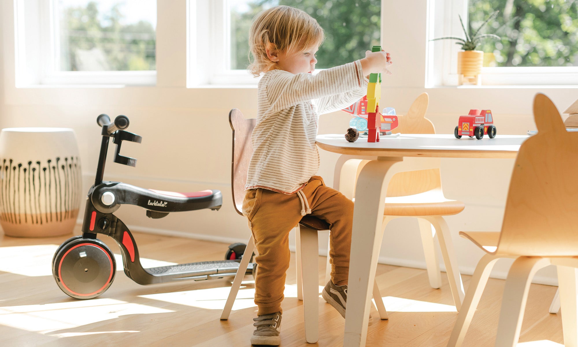 toddler playing with toys and red balance bike