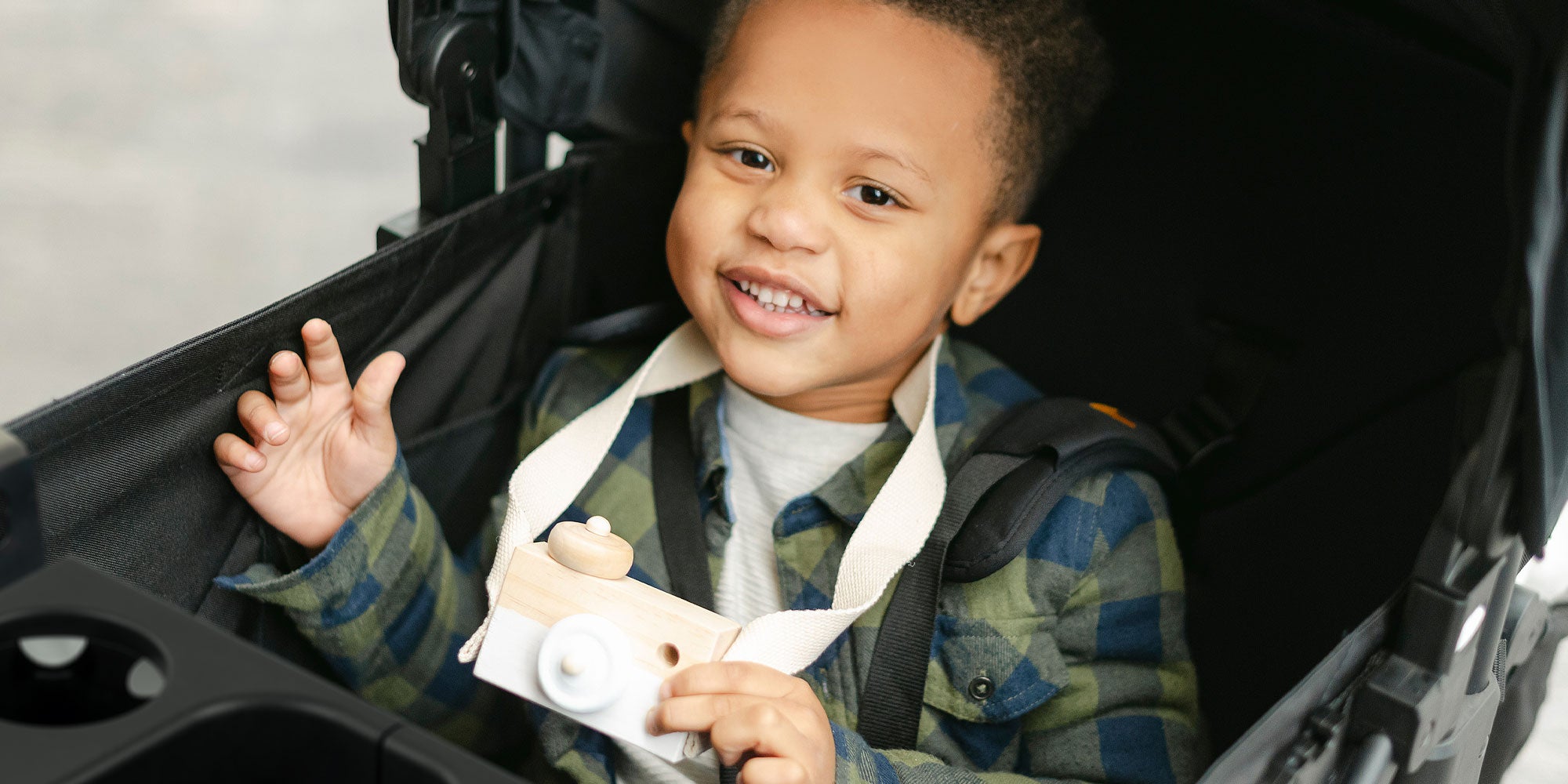 toddler boy with camera toy in stroller wagon with snack tray and cup holders