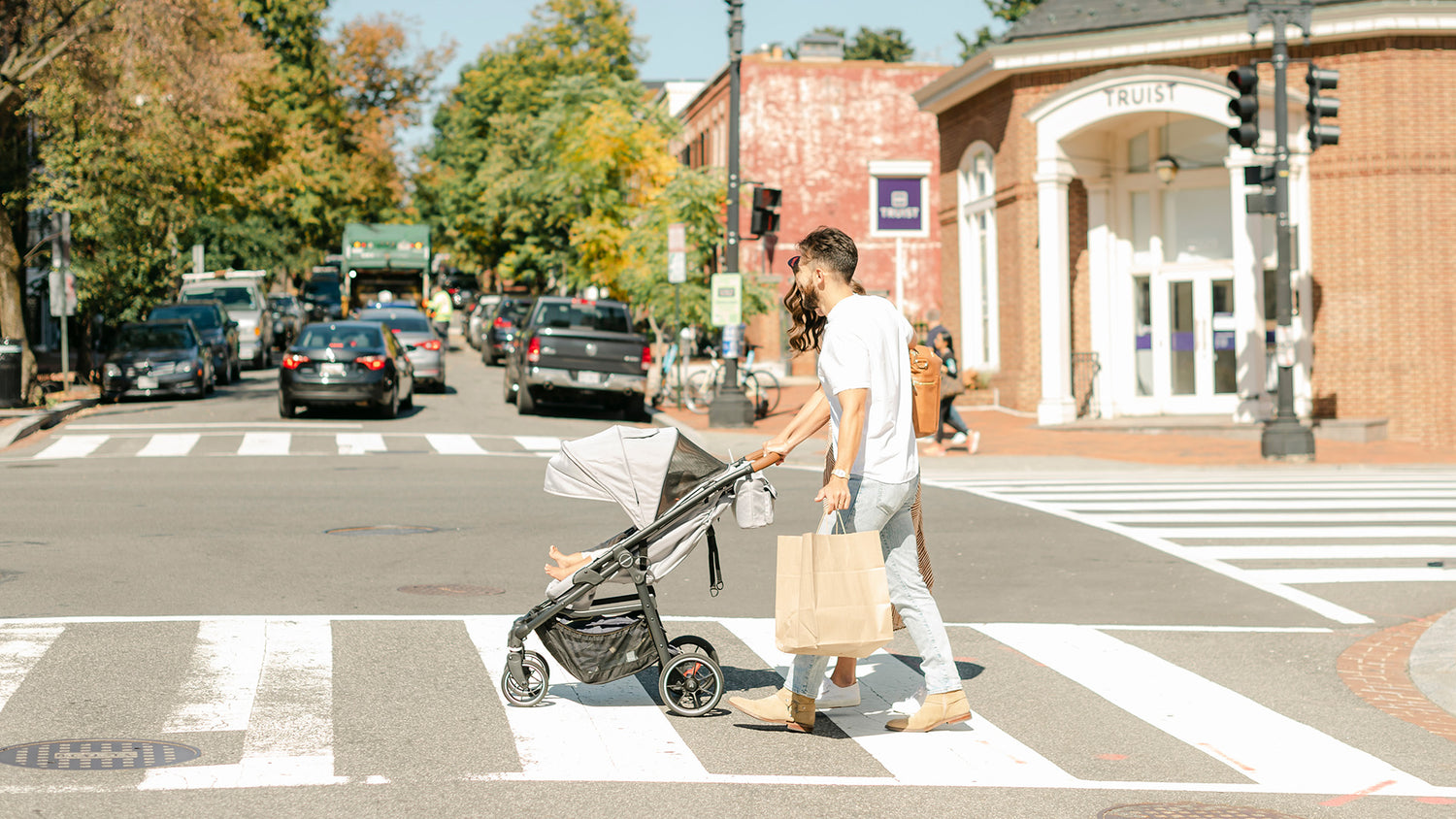 parents crossing road pushing grey crossover convertible stroller wagon with baby in stroller mode
