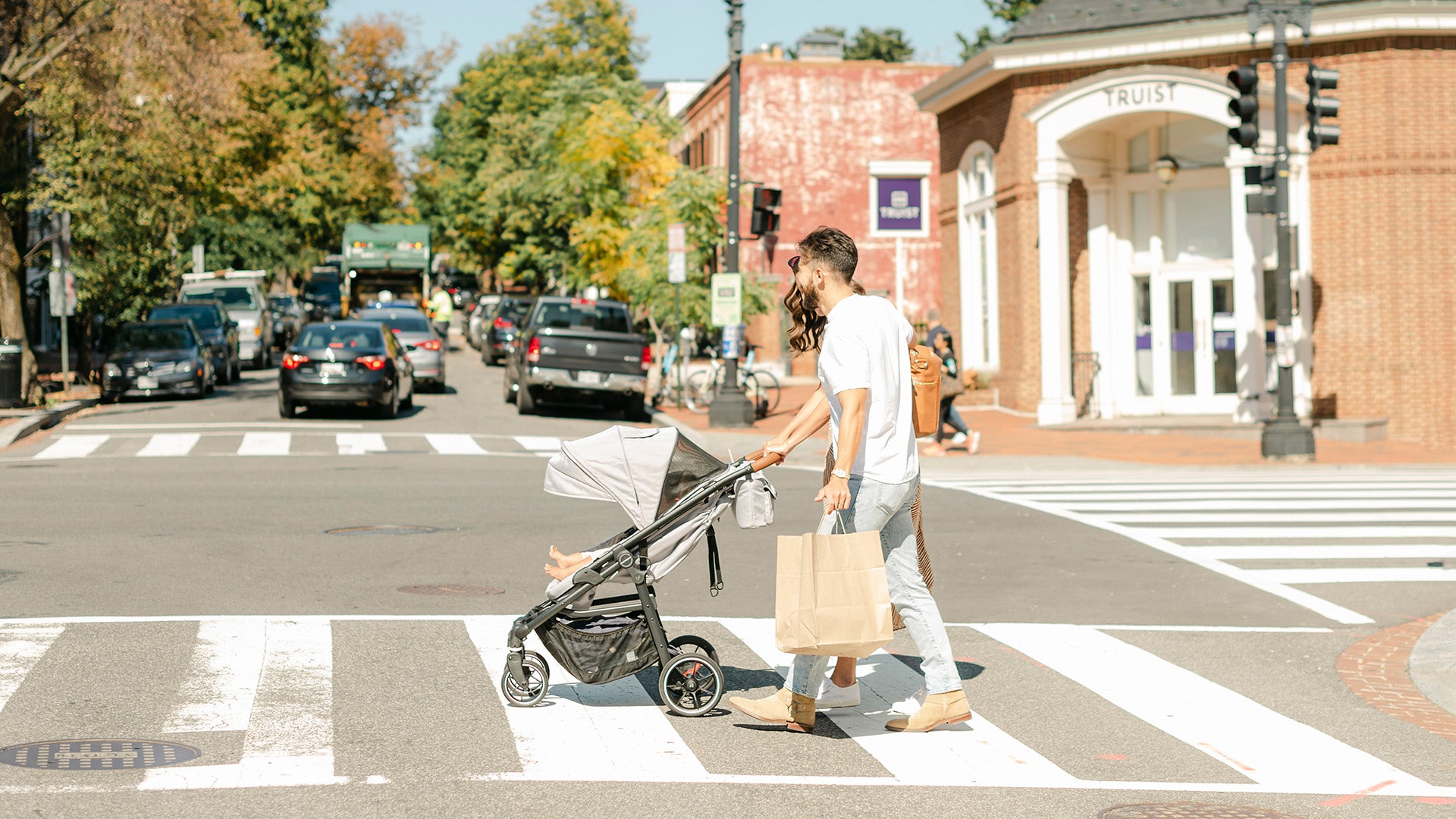 parents crossing road pushing grey crossover convertible stroller wagon with baby in stroller mode